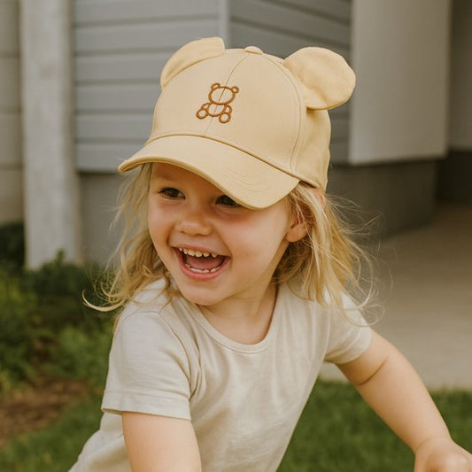 fille souriante portant casquette bebe beige